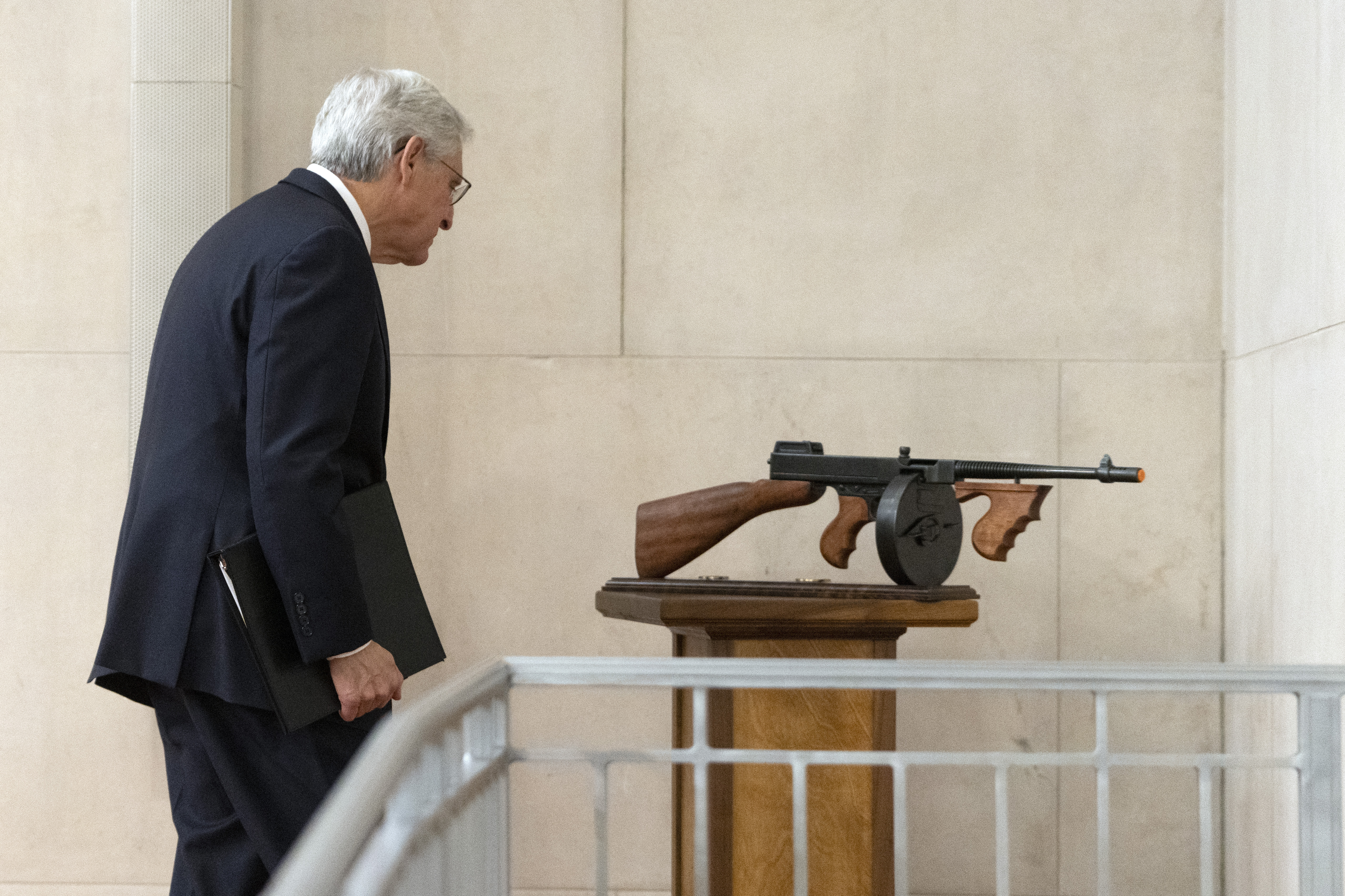 Attorney General Merrick Garland looks at a tommy gun given to him as a gift by FBI Director Christopher Wray after a farewell ceremony at the Department of Justice, Thursday, Jan. 16, 2025, in Washington. (AP Photo/Mark Schiefelbein)