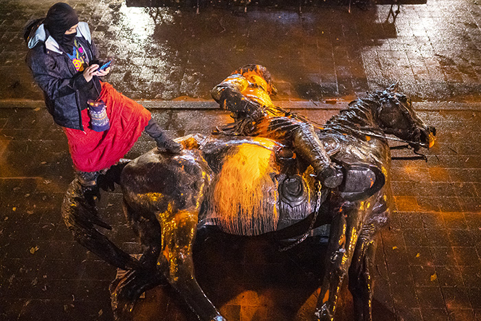 A protester stands over a toppled statue of President Theadore Rosevelt during an Indigenous Peoples Day of Rage protest on October 11, 2020, in Portland, Oregon.