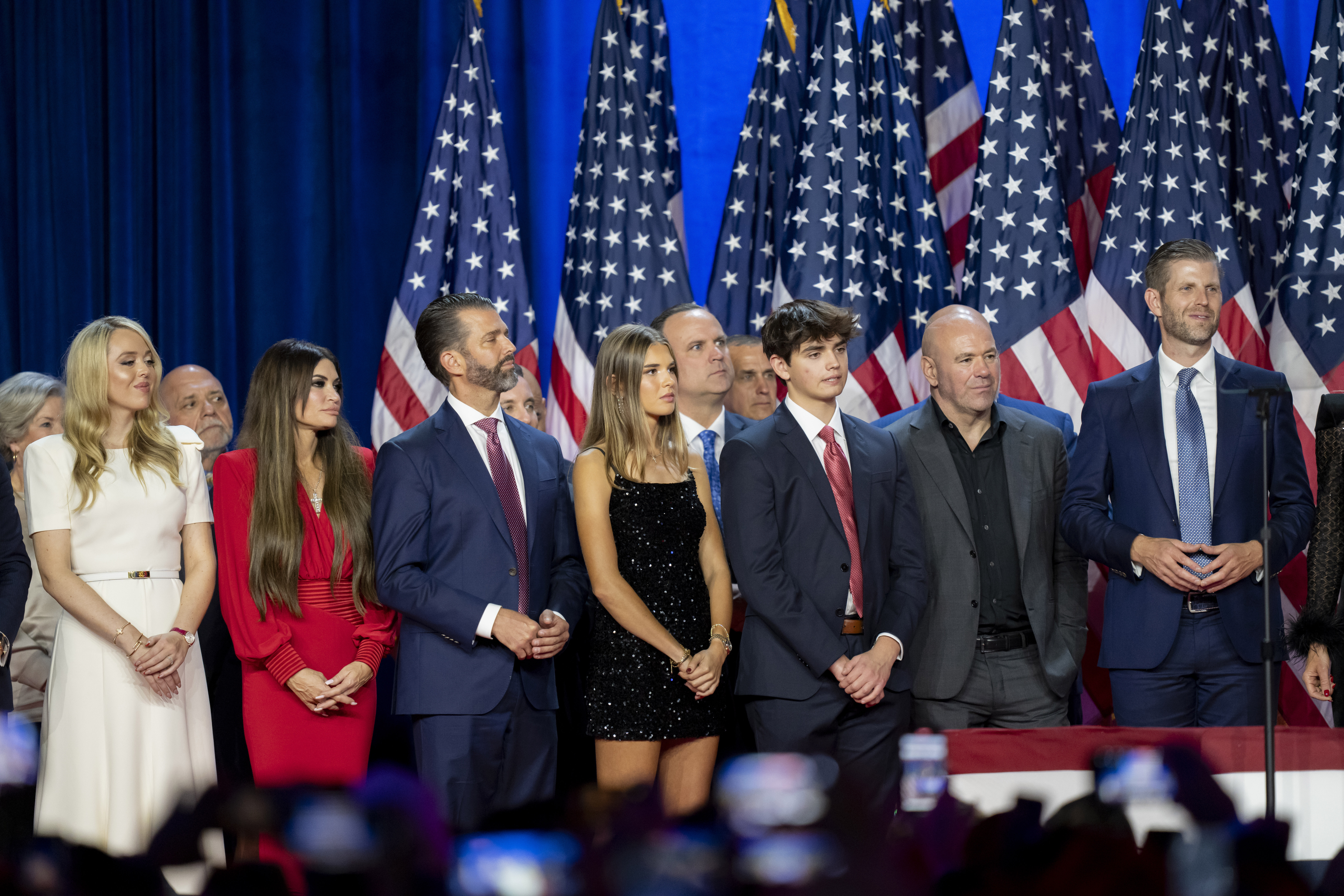 From left, Susie Wiles, Tiffany Trump, Tony Fabrizio, Kimberly Guilfoyle, Donald Trump Jr., Walt Nauta (hidden two people), Kai Madison Trump, Dan Scavino, Corey Lewandowski, Donald Trump III, Dana White, Chris LaCivita and Eric Trump, listen as Republican presidential nominee former President Donald Trump speaks at an election night watch party Wednesday, Nov. 6, 2024, in West Palm Beach, Fla.