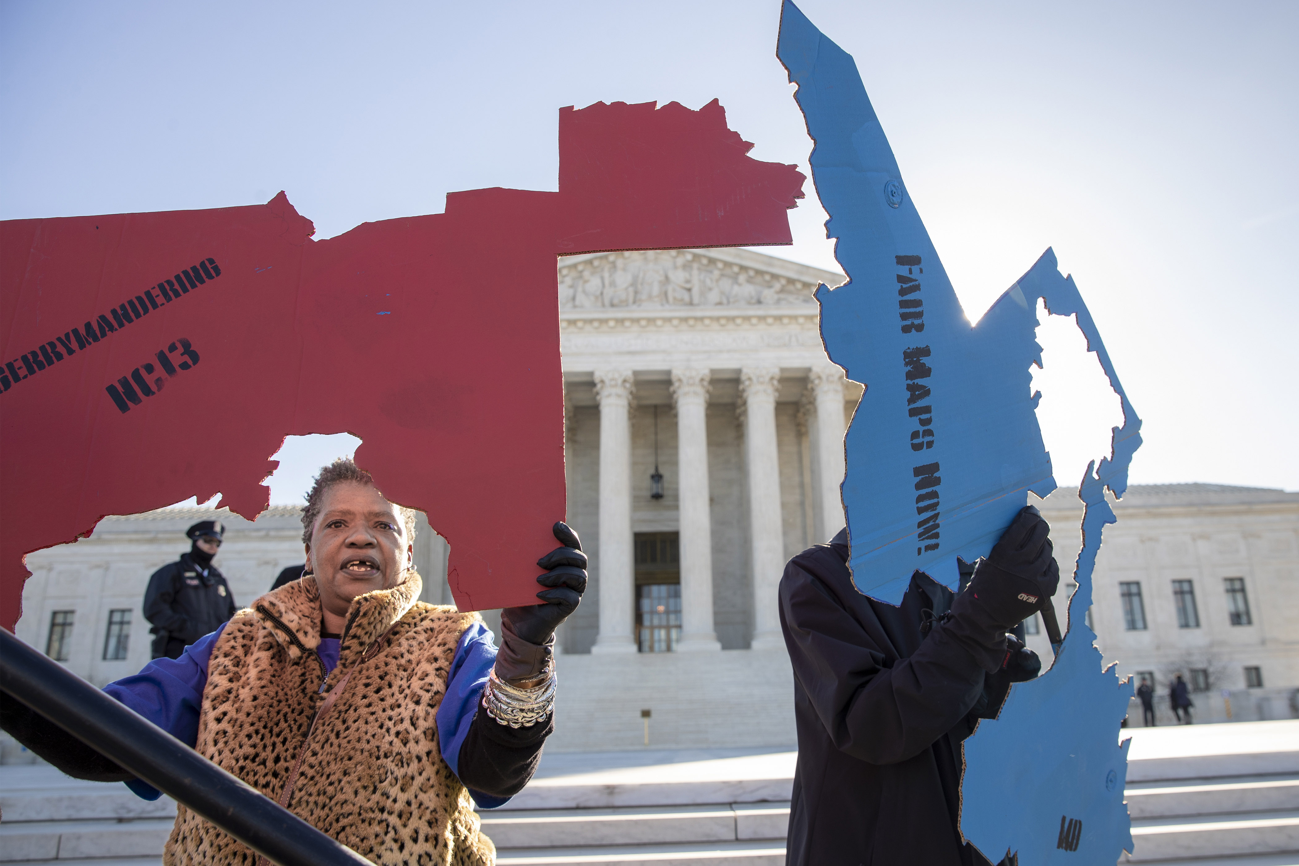 Activists at the Supreme Court opposed to partisan gerrymandering hold up representations of congressional districts from North Carolina, left, and Maryland, right, as justices hear arguments about the practice of political parties manipulating the boundary of a congressional district to unfairly benefit one party over another, in Washington, March 26, 2019.
