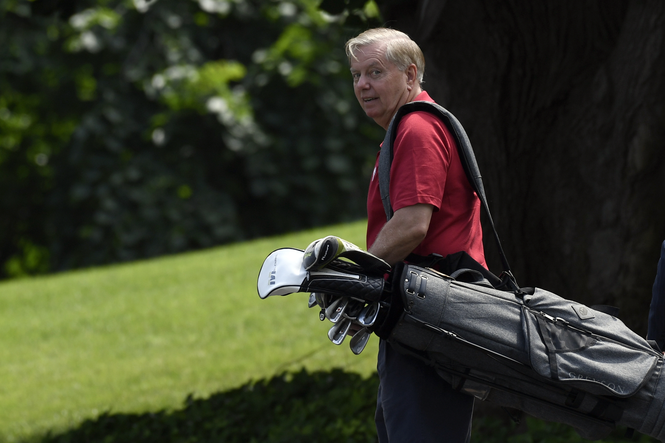 Graham, seen carrying his clubs at the White House in 2019, made his initial pitch on Iran on a golf course. 