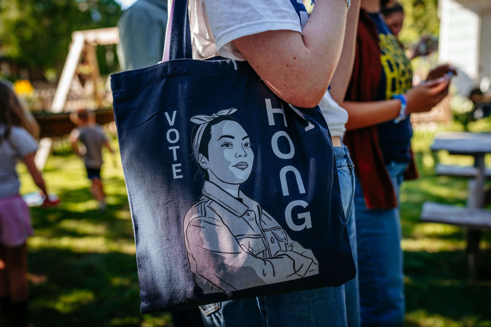 A person holds a “Vote Hong” tote bag in a backyard in Oshkosh.