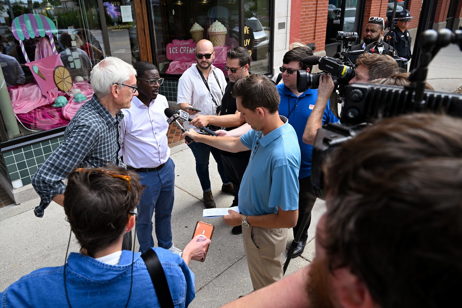 Evers, left, and David Crowley speak to reporters during a campaign stop outside Word Haven Book House in Sheboygan.