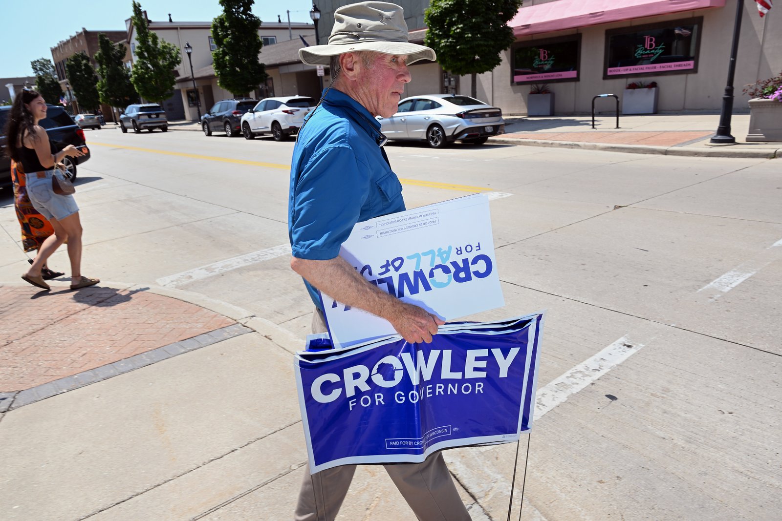 A Crowley supporter holds campaign signs outside Urbane restaurant, where Crowley spoke during a campaign event, in Sheboygan on Aug. 7.