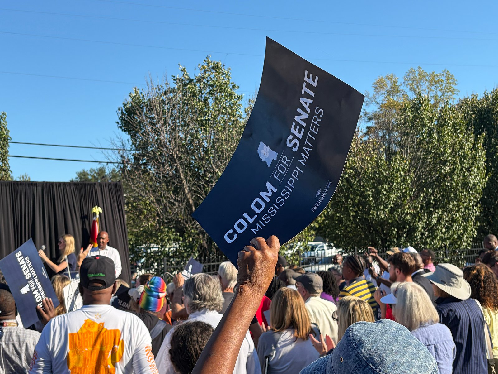 Supporter waves a “Colom for Senate” campaign sign at a rally with Sen. Raphael Warnock in Jackson, Mississippi. 